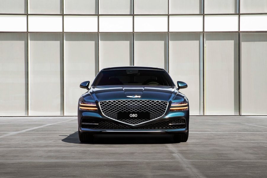 A blue 2023 Genesis G80 parked in front of a building.