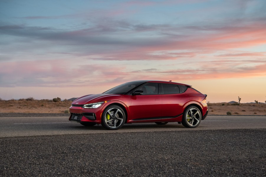 Red 2023 Kia EV6 at sunset driving on the road.