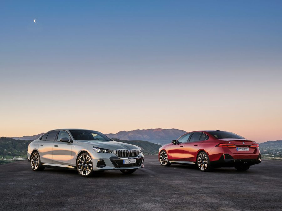 A white and red 2024 BMW 5 Series gas and electric sedan parked next to each other