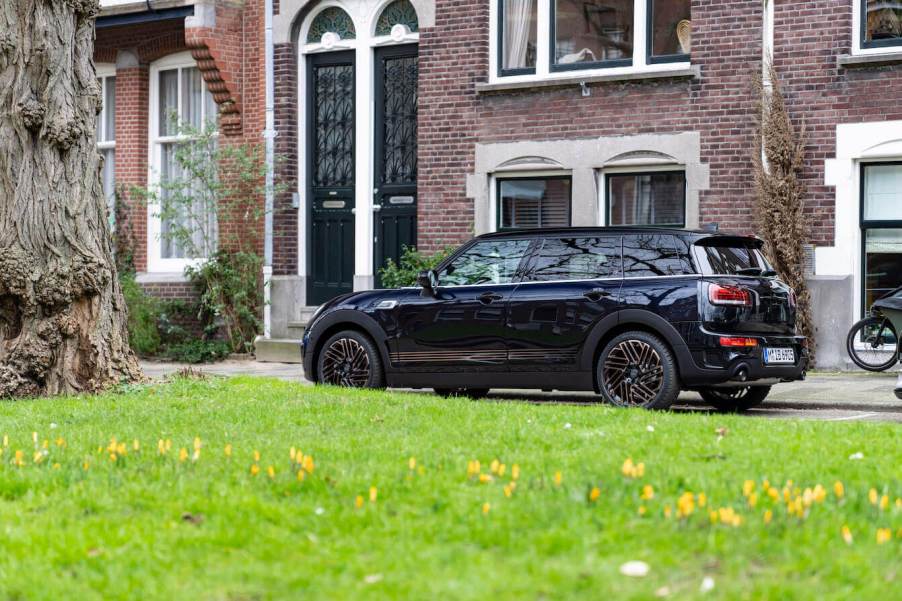 The black 2024 Mini Clubman in front of a building with green grass next to it.