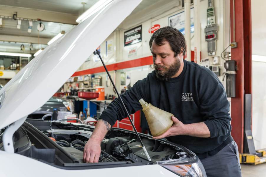 An auto mechanic completes an oil change on a customer's vehicle. Oil change is part of the maintenance schedule.