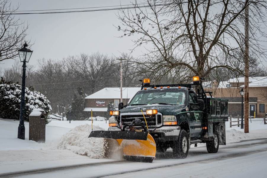 A ford F-Series pickup heavy duty plow truck clears a road and uses strobe lights to warn nearby motorists.