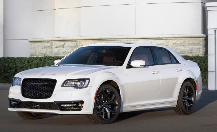 A white 2023 model year Chrysler 300 sedan parks alongside a large structure.