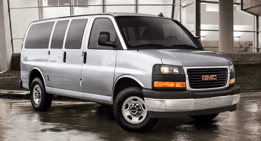 A 2023 GMC Savana full-size passenger van model parked on wet concrete