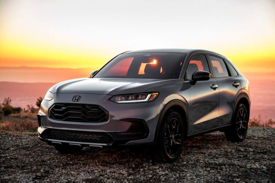 A gray 2024 Honda HR-V Sport parked on gravel before a sunset