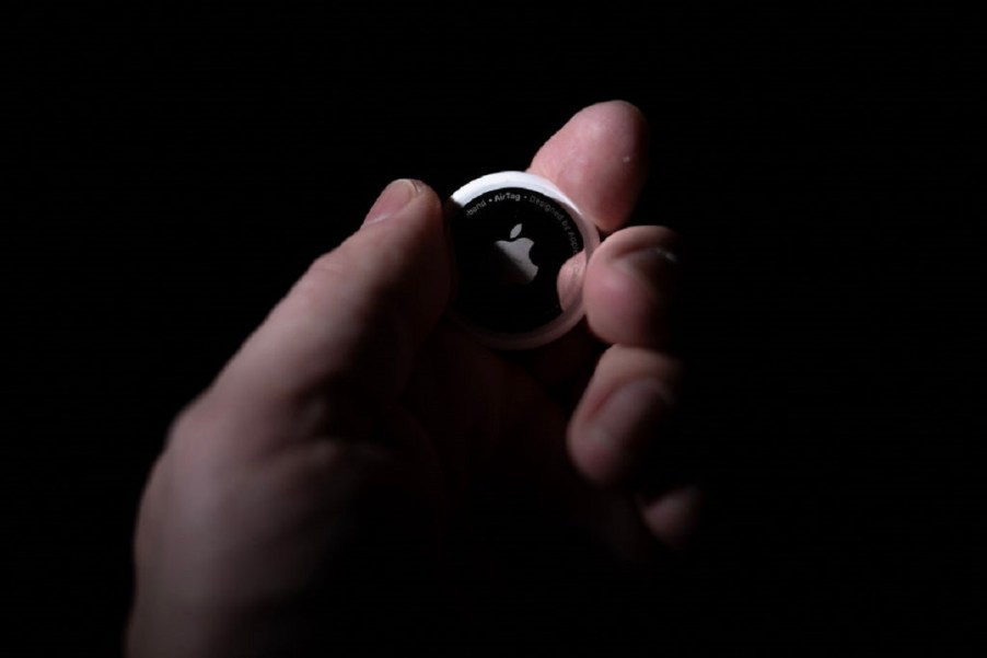 A person holds an Apple AirTag in the dark.