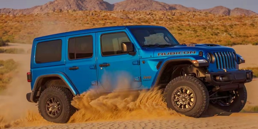 A blue 2023 Jeep Wrangler Rubican 392 is driving in sand.