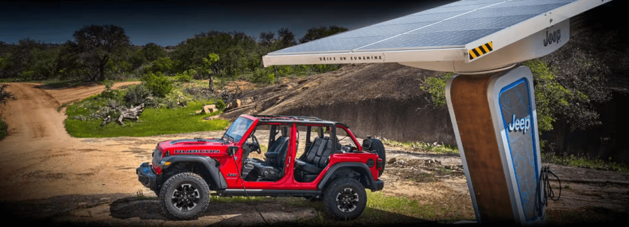 A red Jeep Wrangler Rubicon 4xe plug-in hybrid (PHEV) model near a solar-powered EV charging station