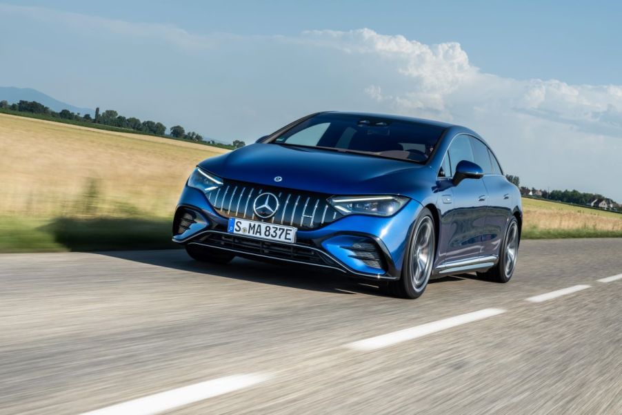 A Mercedes-AMG EQE Sedan European model driving down a country highway past wheat fields