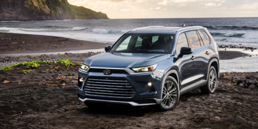 A blue 2024 Toyota Grand Highlander is parked near water.