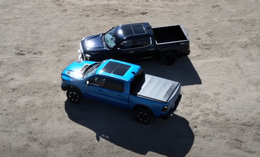 This is a Ram 1500 Rebel and Toyota Tundra Limited next to one another in a gravel parking lot.