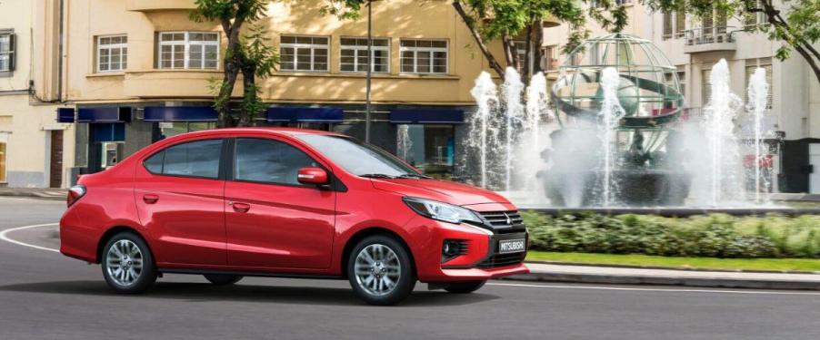 A 2023 Mitsubishi Mirage G4 subcompact sedan model driving past a park water fountain