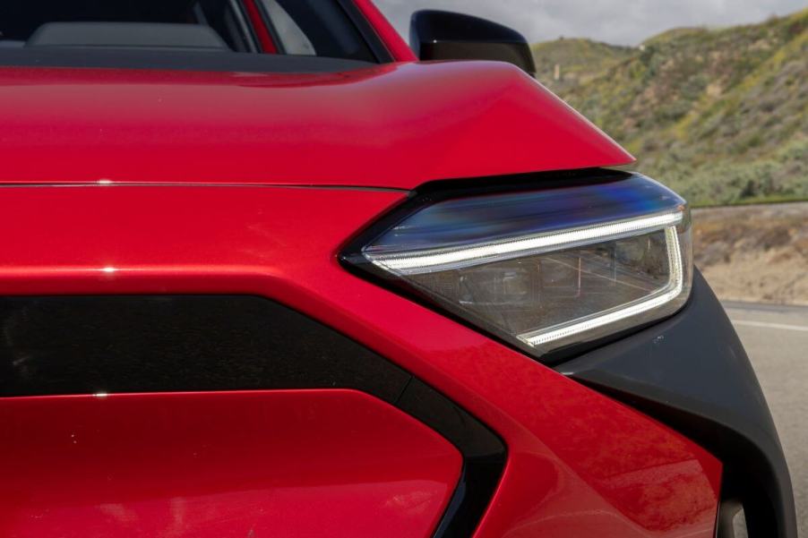 A 2023 Subaru Solterra electric compact SUV model shot of an illuminated headlight near the grille and cladding