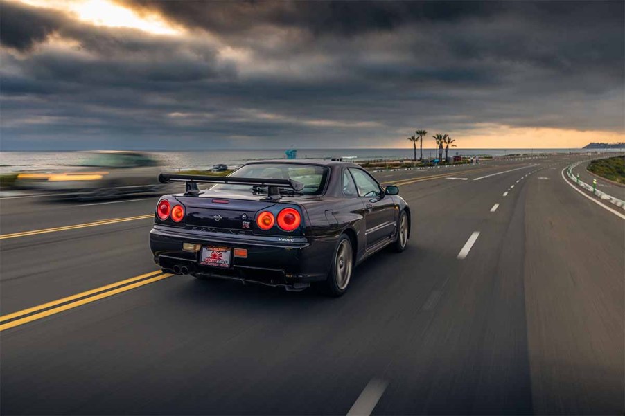 R34 Nissan Skyline GT-R V-Spec Midnight Purple II Driving Down Beach in Sunset