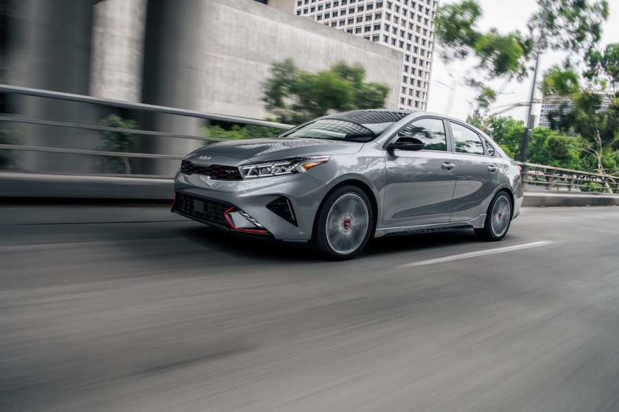 One of the most affordable Kia sedans is the Kia Forte, pictured in silver/gray speeding down a city road.