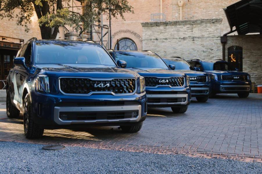 A line of four 2024 Kia Telluride midsize SUV models parked on a cobblestone plaza