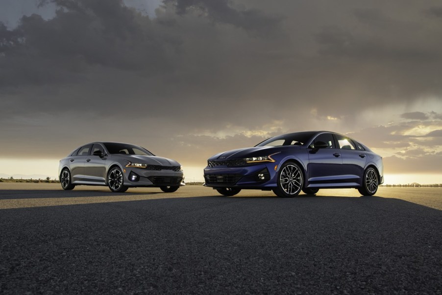 Two 2023 KIa K5 models on display at sunset.