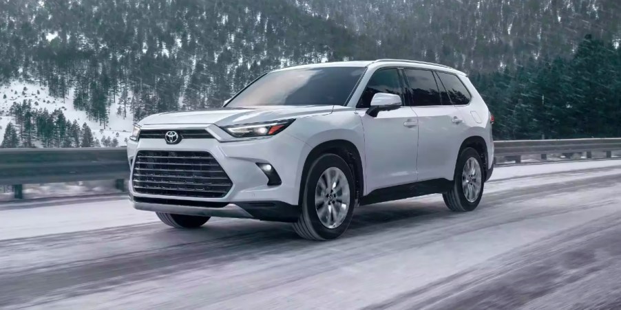 A white 2024 Toyota Grand Highlander is driving on the road.