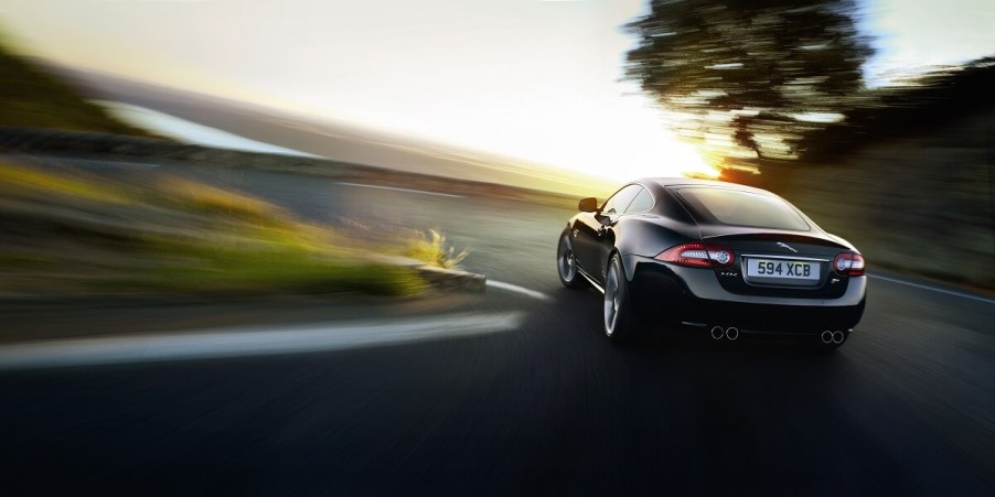 A black Jaguar XKR corners hard on an uphill road.