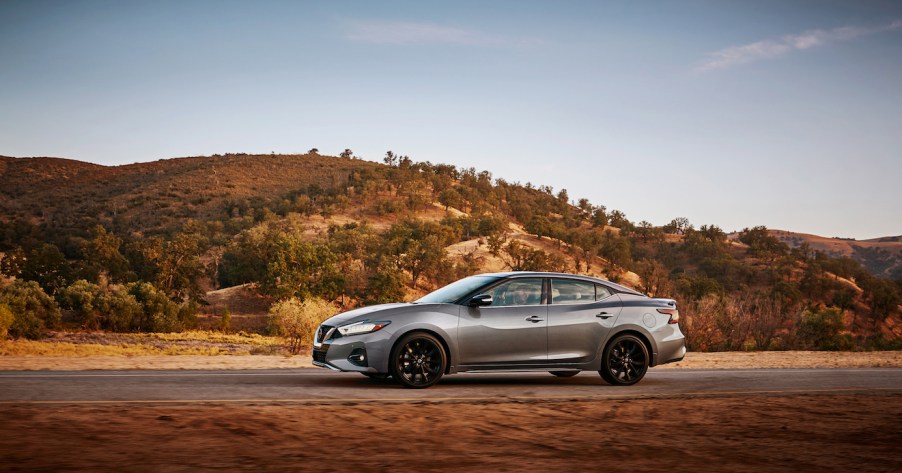 Gray Nissan Maxima driving on a desert road. Nissan Maxima trims offer a bunch of variety for car shoppers