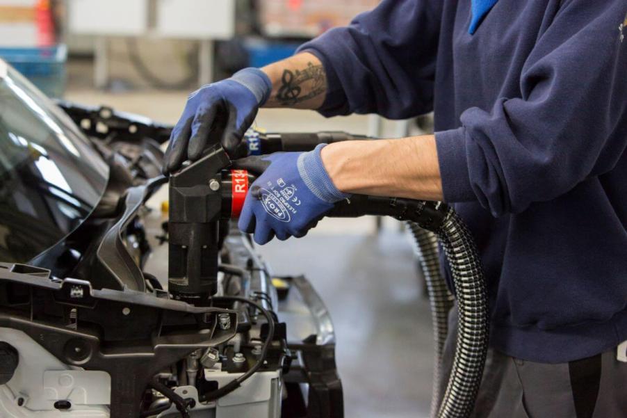 A Daimler AG employee adding oil, water, and brake fluid to a Smart Car model on the assembly line