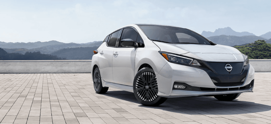 A 2024 Nissan Leaf all-electric hatchback model parked on a brick tile plaza in the mountains