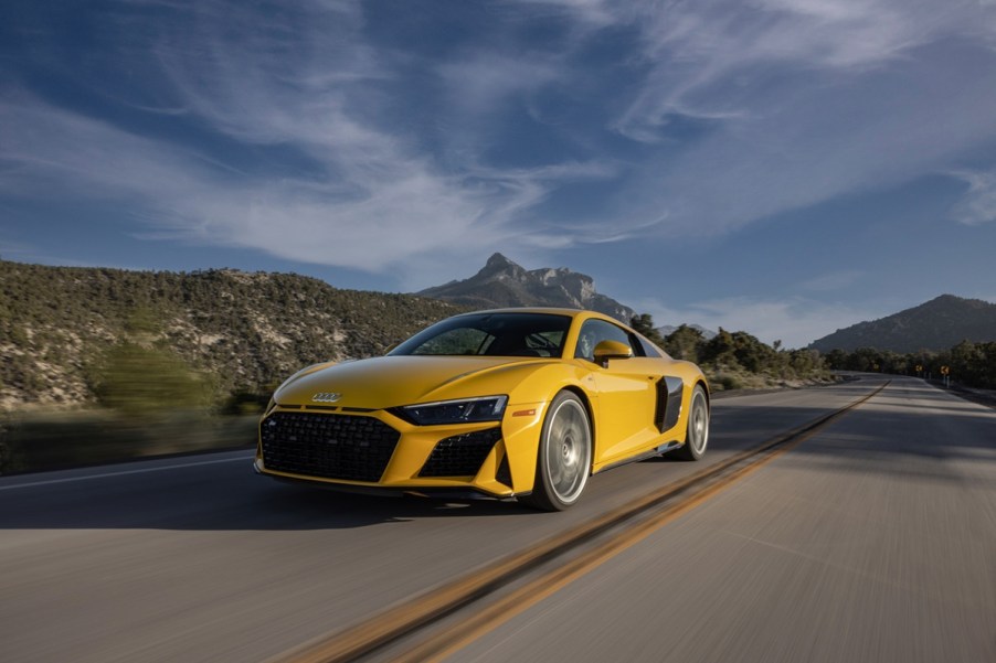 Bright yellow 2023 Audi R8 one of the cheapest supercars you can buy new in 2023 driving on road front 3/4