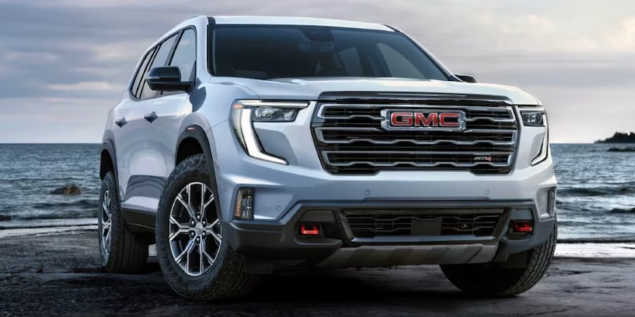 A white 2024 GMC Acadia midsize three-row SUV is parked outdoors.