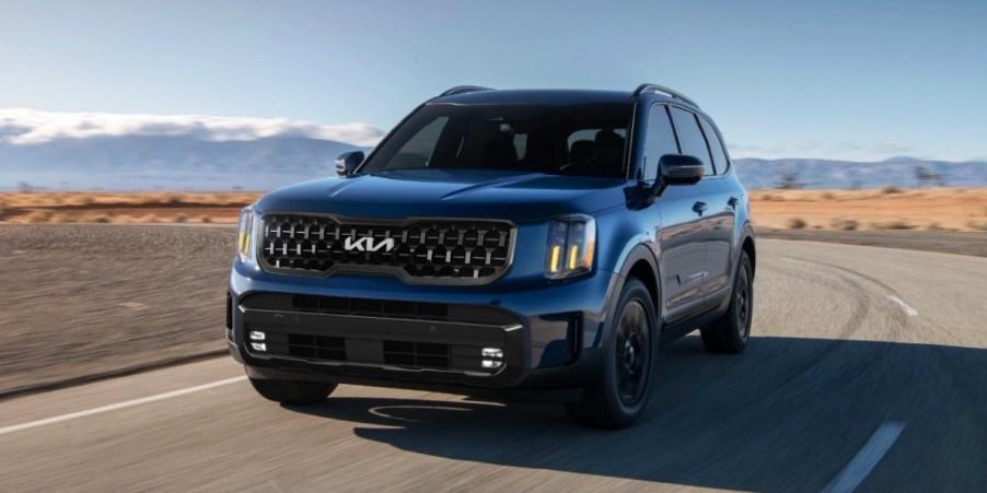 A blue 2024 Kia Telluride driving on an open road.