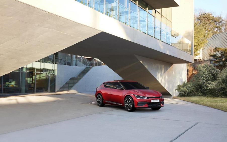 The top Kia EV – the 2023 Kia EV6 – pictured in red parked underneath a modern building.