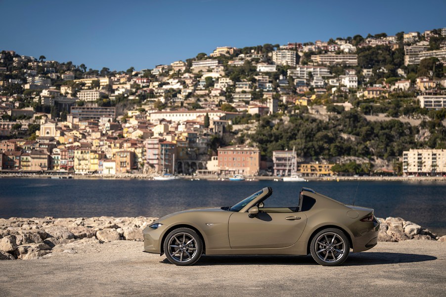 Side profile view of a 2023 Mazda MX-5 Miata in tan parked alongside a desert road