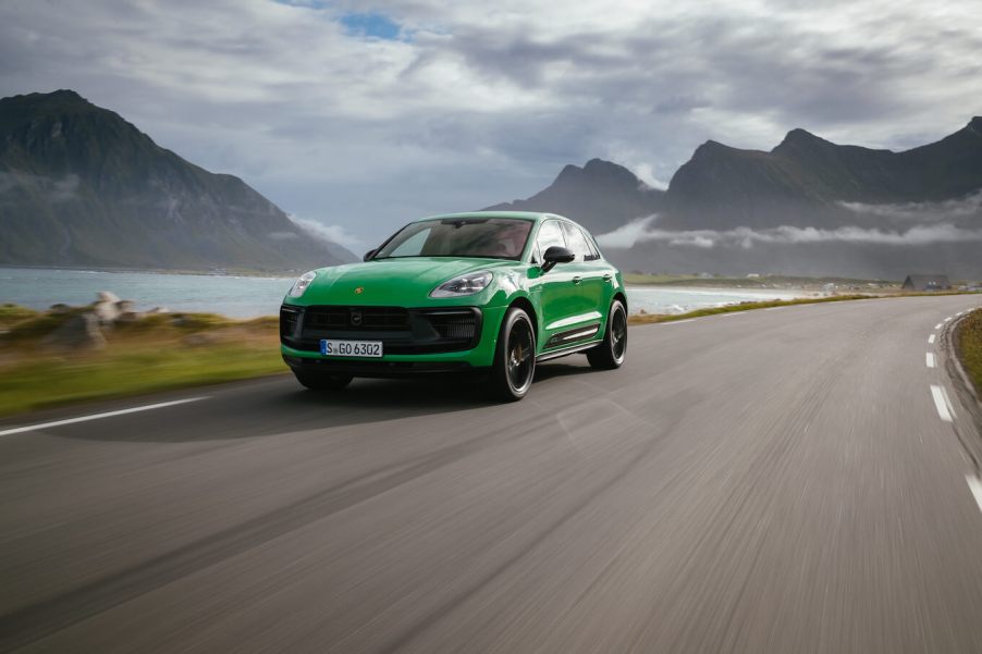 A green 2024 Porsche Macan driving down a scenic road.