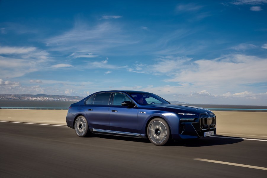 A blue BMW 7 Series driving down a desert road with blue skies. BMW 7 Series resale value is on the lower end.