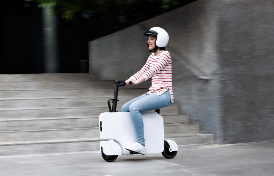 A person riding on a Honda Motocompacto electric scooter.