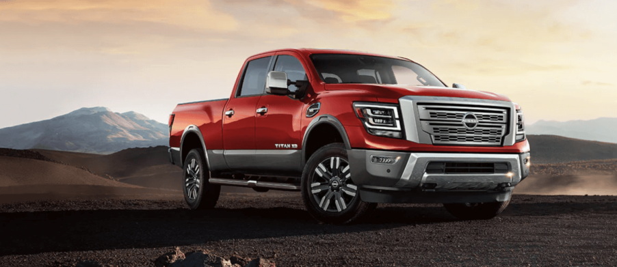 A 2024 Nissan Titan XD heavy-duty pickup truck model parked on a dirt plain near hills and under clouds