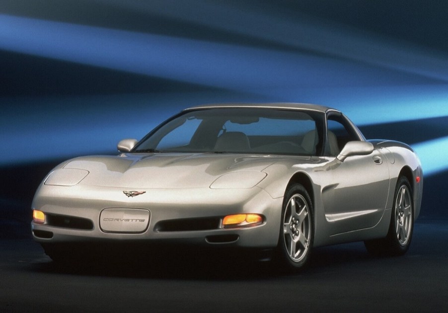 A silver Chevrolet C5 Corvette sits on a stage next to a blue backdrop.