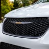 The 2023 Chrysler Pacifica Road Tripper features unique exterior Brilliant Orange badging, wheel accents and graphics. White Chrysler minivan front grille.