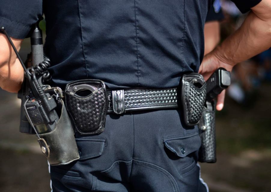 The back of a police officer who has his hand on his gun.