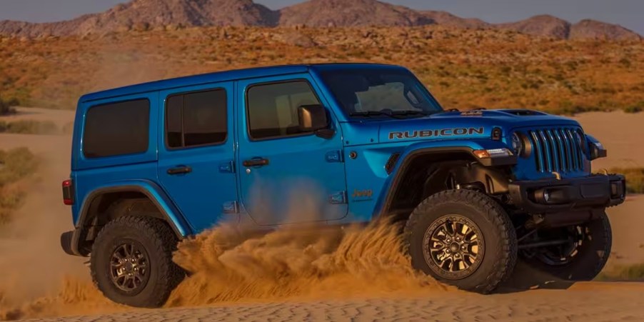 A blue Jeep Wrangler 4xe small plug-in hybrid SUV is driving off-road.