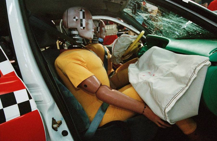 A crash test dummy in the front seat of a truck.