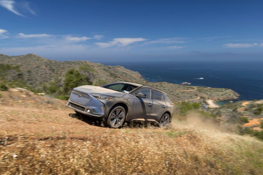 A 2023 Subaru Solterra all-electric compact SUV model covered in dust driving on off-road country trails