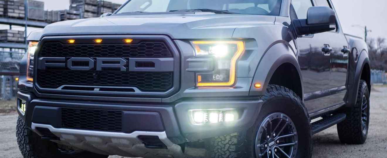 A Ford truck parked at left front angle with lights on