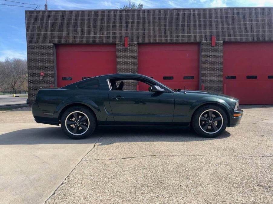 A Dark Highland Green 2008 Ford Mustang Bullitt, like the American muscle car in 'Superstore,' shows off its front end next to a firehouse.