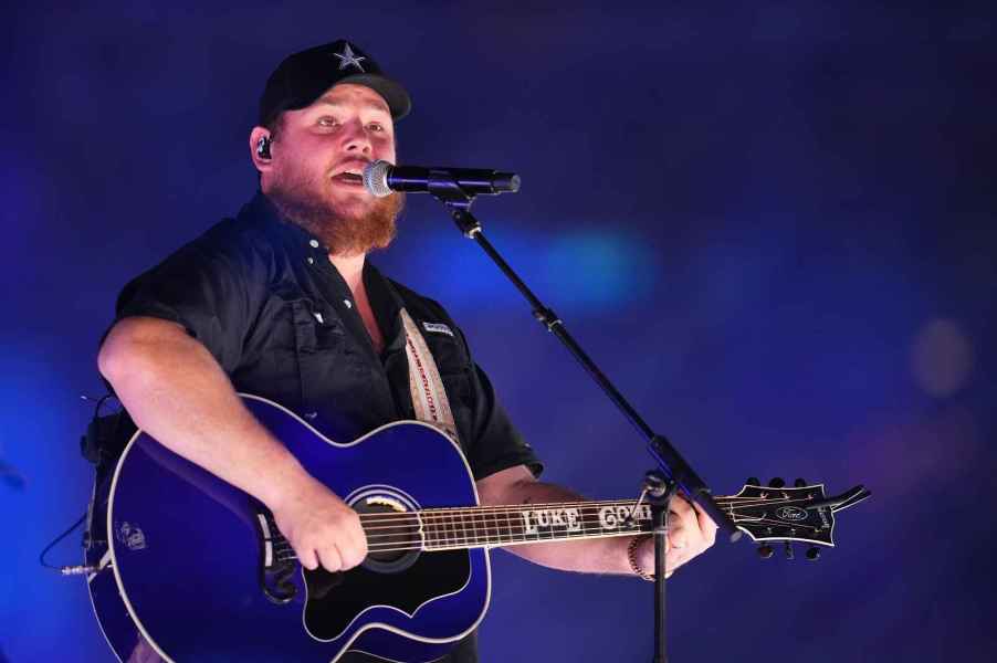 Luke Combs singing onstage while playing guitar