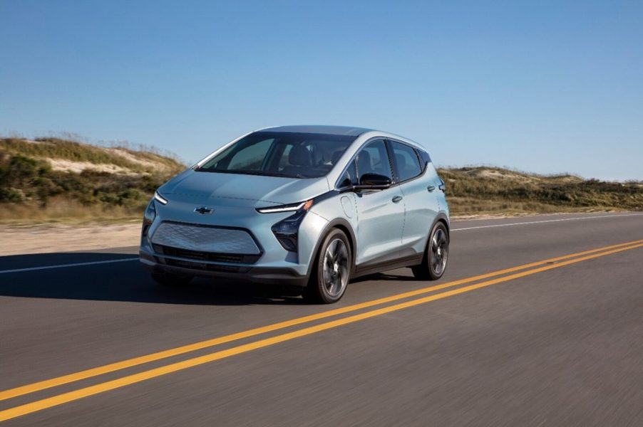 A Chevrolet Bolt EV drives across a desert highway.