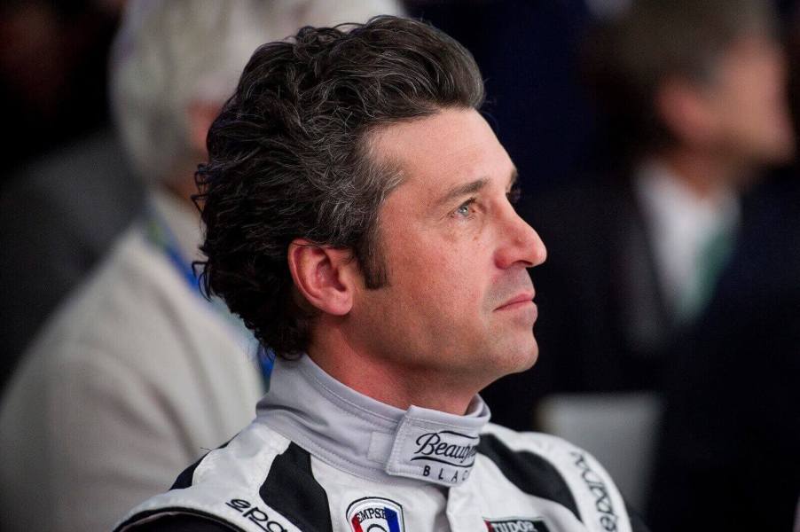 Patrick Dempsey, racing driver and actor, looks away in a racing suit.