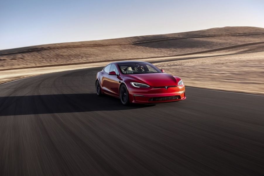 A bright-red Tesla Model S EV takes a corner on a track.