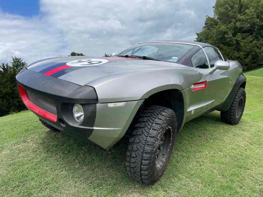 The grille and front headlight of a lifted sports car parked on grass.