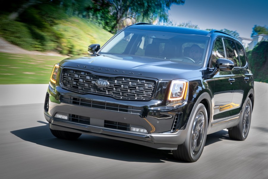 A black 2021 Kia Telluride driving on a road at left front angle