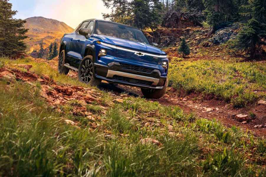 A blue 2024 Chevrolet Silverado EB drives down a grass covered dirt hill